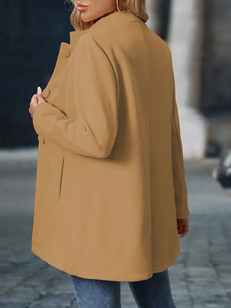 Damski elegancki płaszcz jesienny w ruchu. Widoczne guziki, modny krój, idealny na codzień.