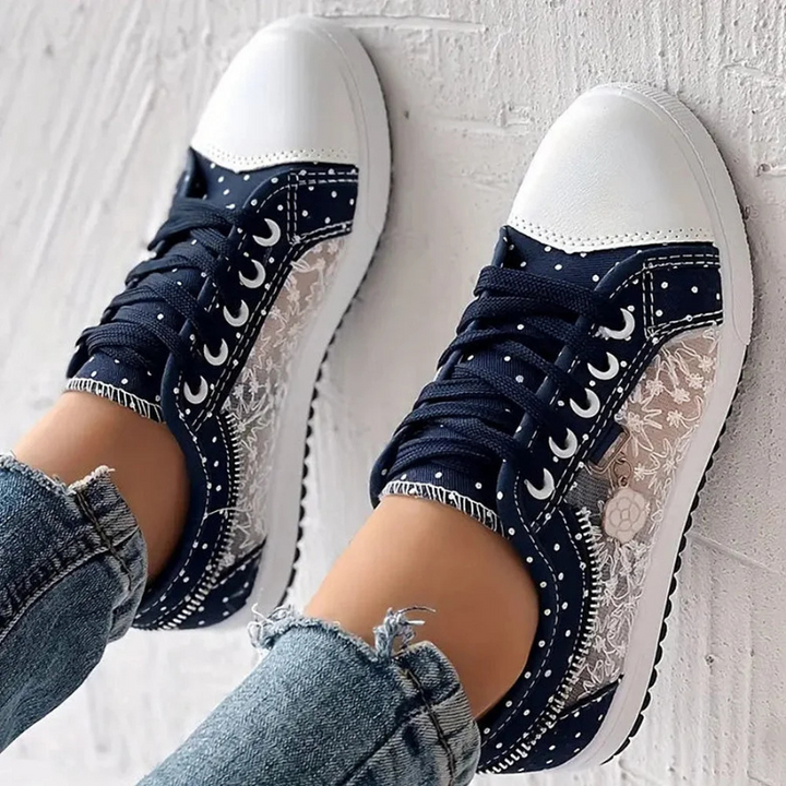 Detal: bliska perspektywa kwiatowego haftu na boku niebieskich damskich sneakersów.