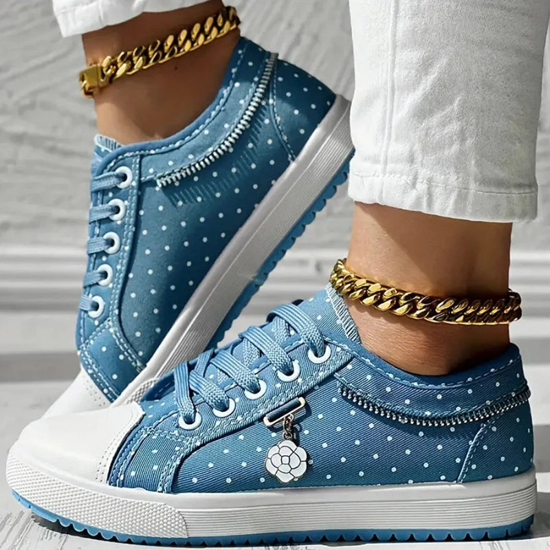 Boczne ujęcie niebieskich damskich sneakersów z haftem kwiatowym, podkreślające ich modny design.