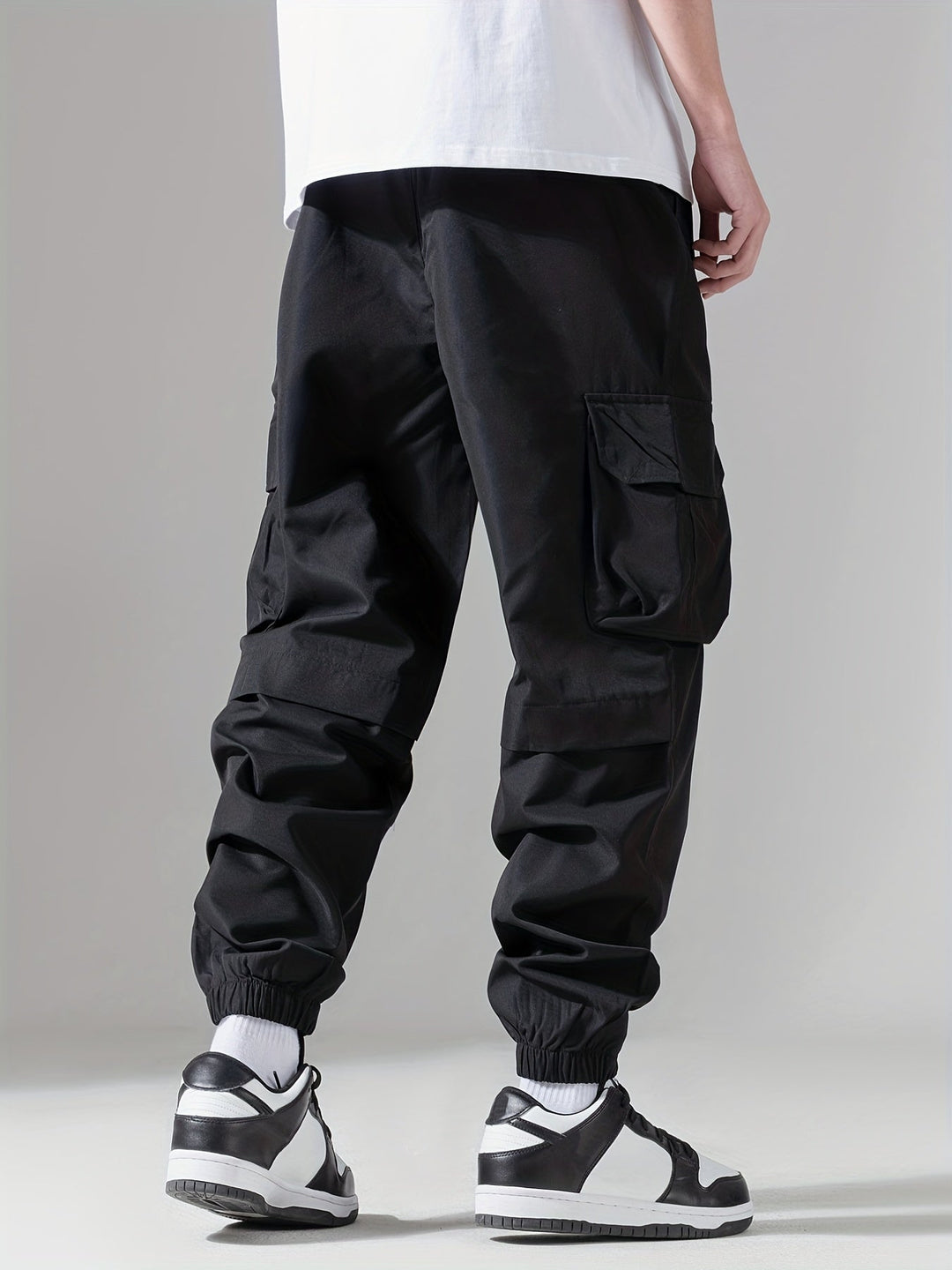 Szczegóły wielofunkcyjnych kieszeni na męskich spodniach cargo joggerach, styl casual.