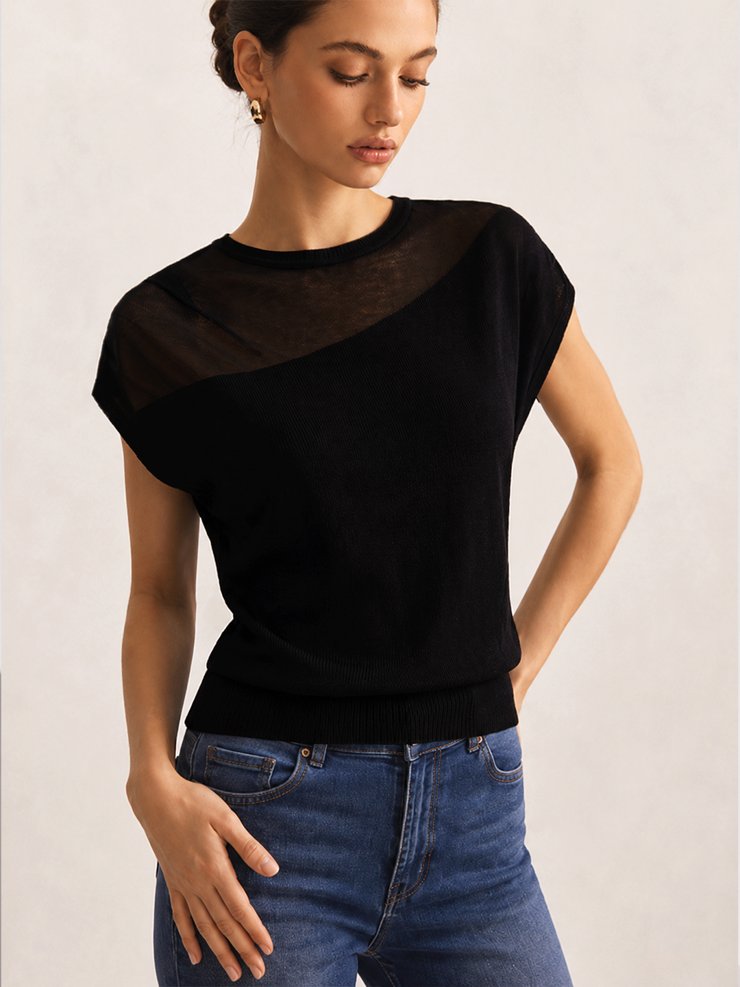 Czarny sweter damski z asymetrycznym, przezroczystym ramieniem. Elegancki, modny styl na wieczór.