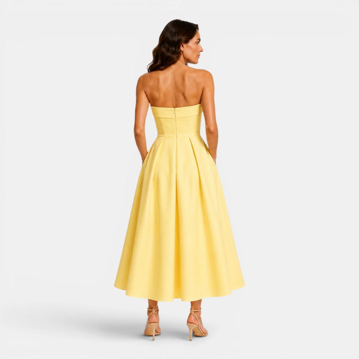 Modelka prezentuje elegancką sukienkę midi plisowaną bez ramiączek. Wieczorowa, imprezowa stylizacja.