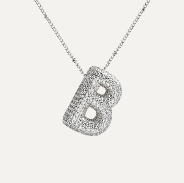Złoty naszyjnik z diamentową literą E, symbol elegancji i osobistego wyrazu.