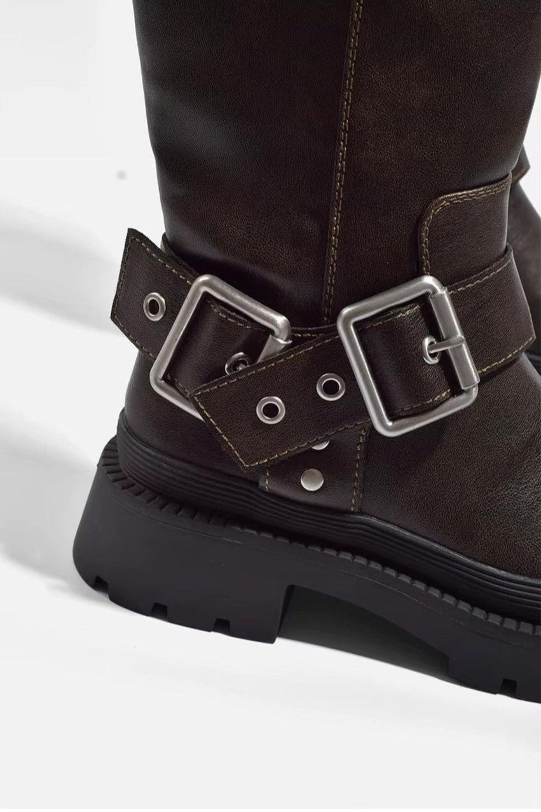 Damskie botki na platformie, widok z boku, z ozdobnymi klamrami. Brązowe, modne buty w stylu retro.