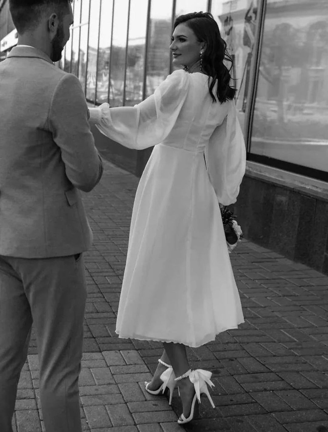 Elegancka biała sukienka midi z rozkloszowanym dołem i dekoltem V. Klasyczny krój z długim rękawem.