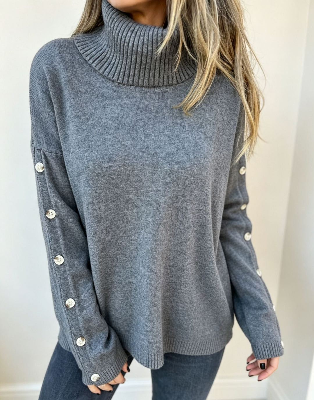 Przedstawia damski sweter oversize z golfem i guzikami, idealny na jesień i zimę.