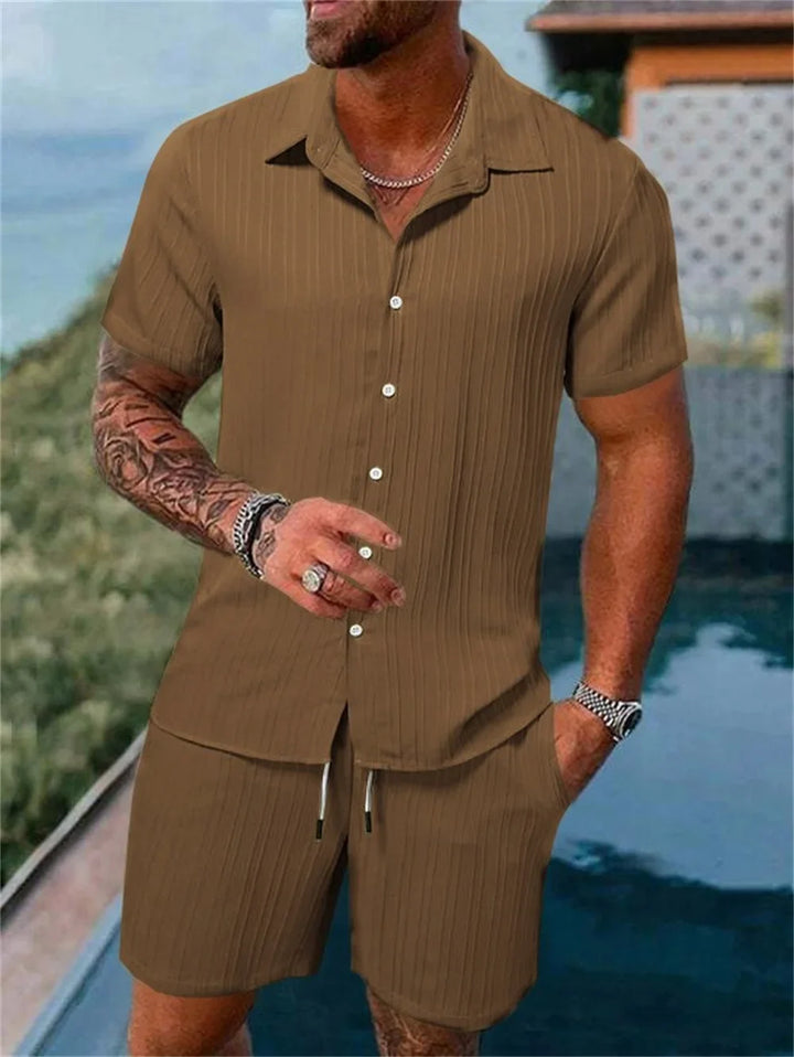 Męski komplet letni w paski na modelu, dynamiczna poza. Modny i swobodny styl.