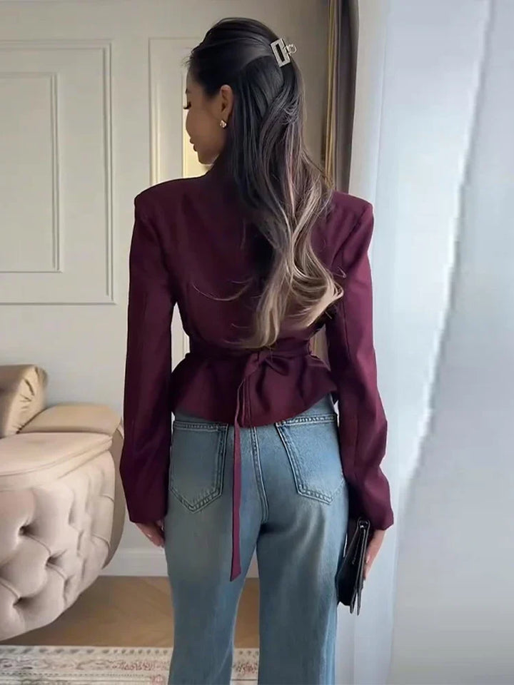 Modelka w czarnej plisowanej marynarce damskiej z dekoltem V. Elegancka, dopasowana, modna do biura.
