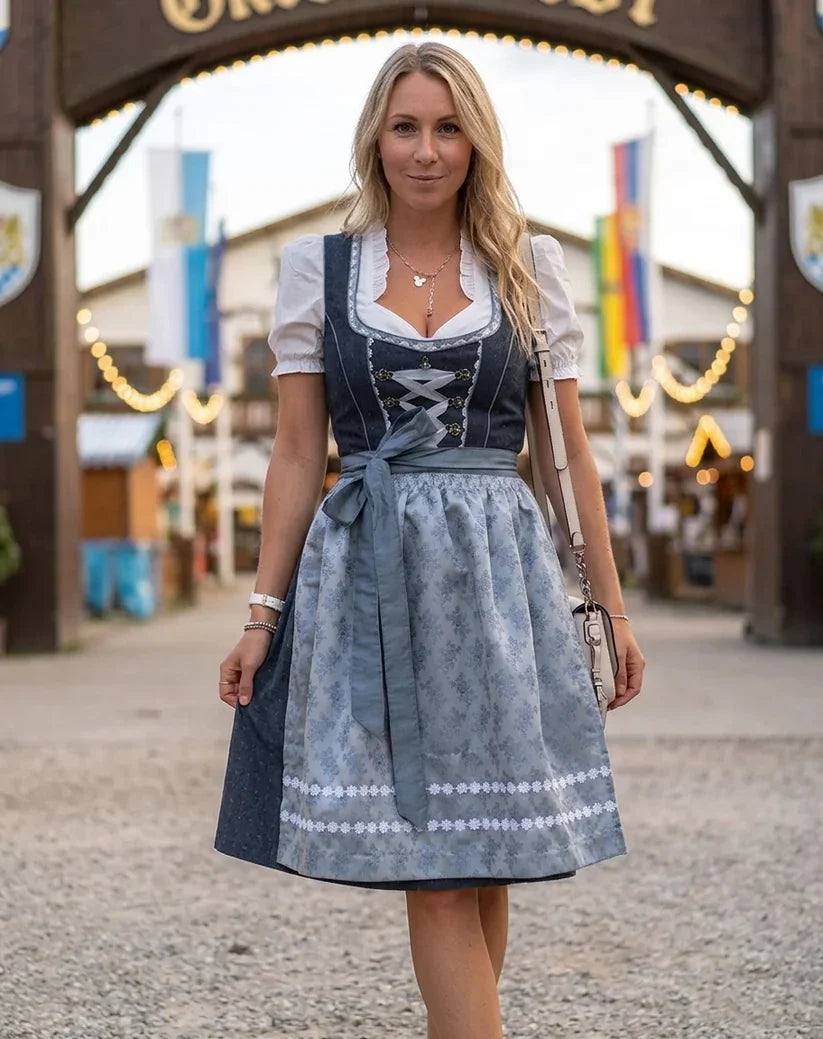 Szara sukienka dirndl damska z ozdobnym dekoltem, białą bluzką i dopasowanym fartuszkiem na Oktoberfest.