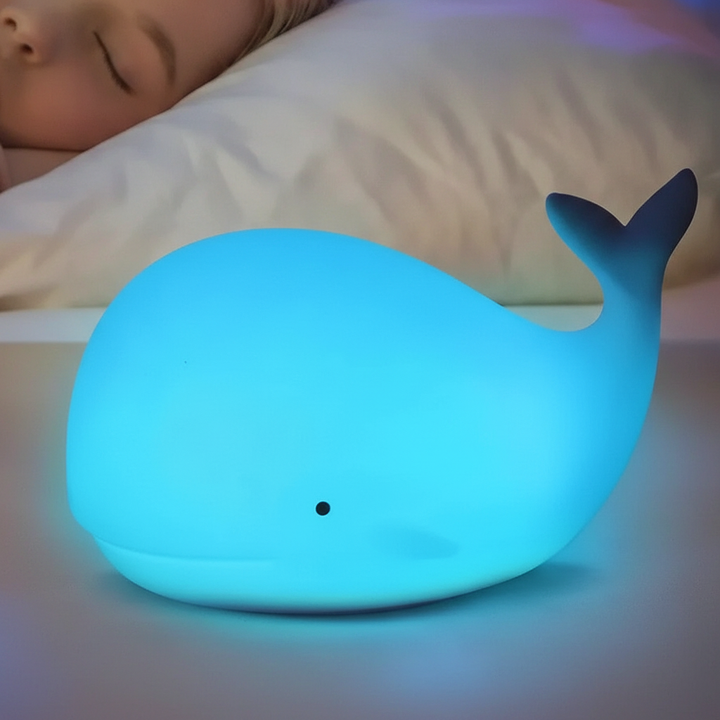 Lampka nocna LED GlowWhale dla dzieci, zapewnia kojące światło w pokoju malucha. Bezpieczny, silikonowy gadżet.