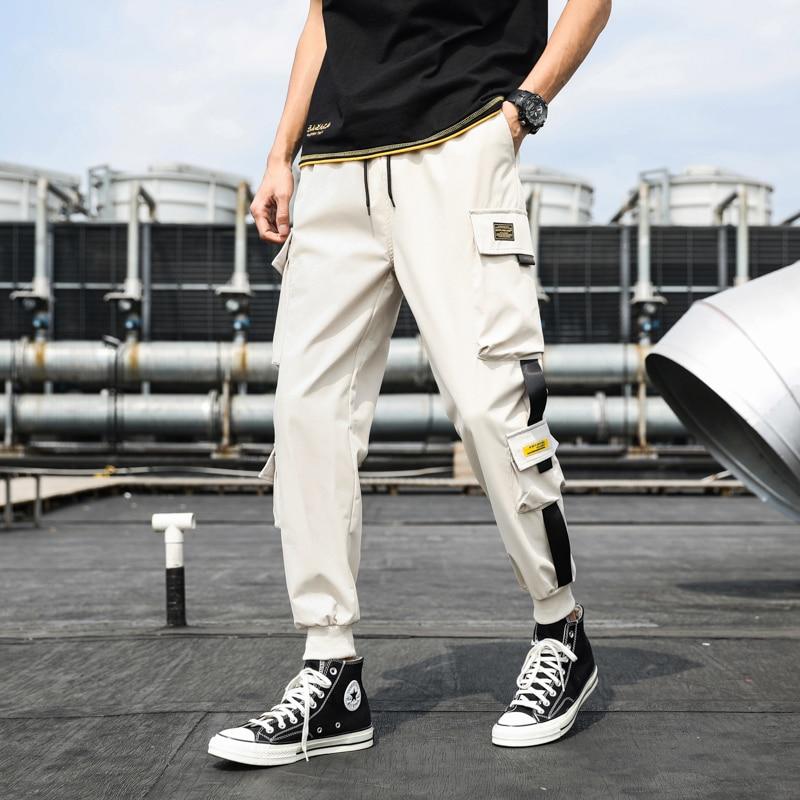 Mężczyzna prezentujący modne męskie bojówki cargo z naszywkami, dopasowane do casualowego outfitu.