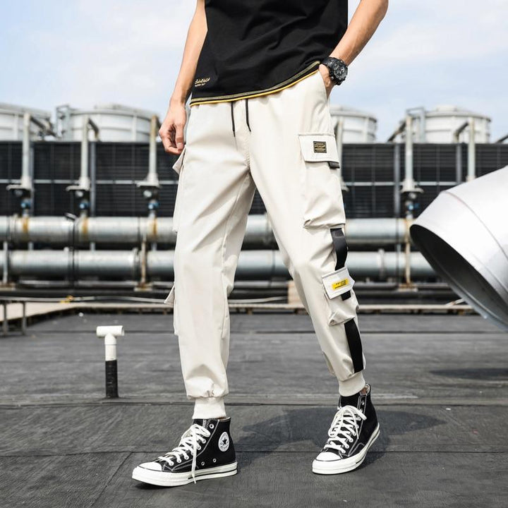 Mężczyzna prezentujący modne męskie bojówki cargo z naszywkami, dopasowane do casualowego outfitu.