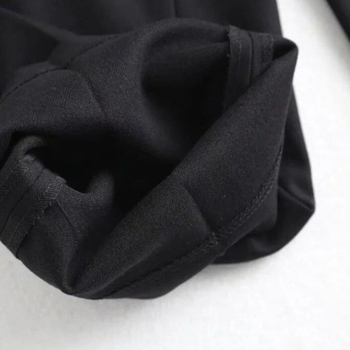 Kobieta prezentująca czarne spodnie paperbag z wiązanym paskiem, wysoki stan, elegancja i wygoda.