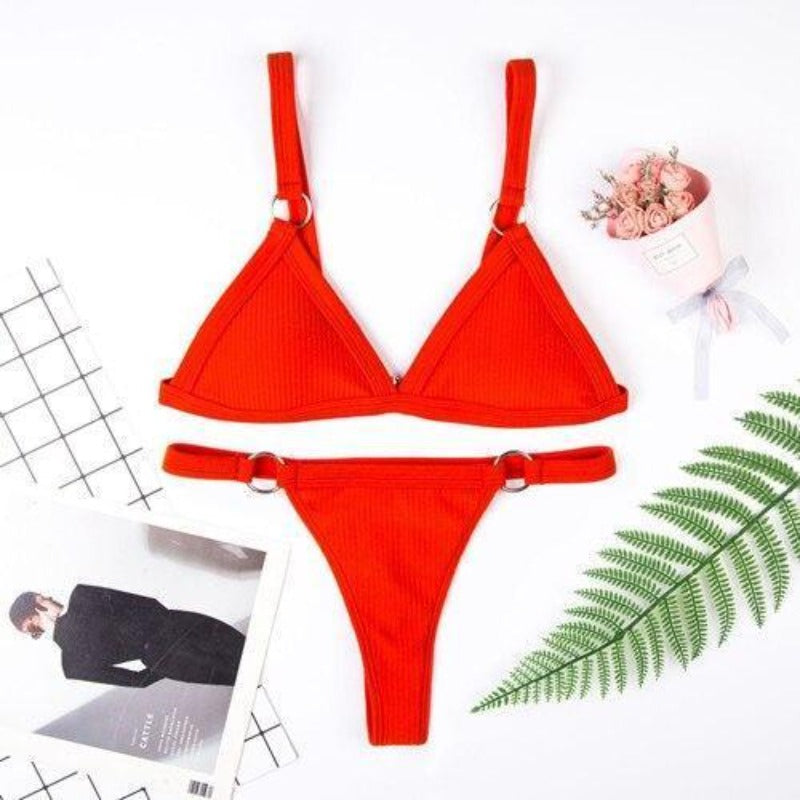 Modelka w modnym prążkowanym bikini damskim z klamrami, prezentująca letni strój kąpielowy na plażę.