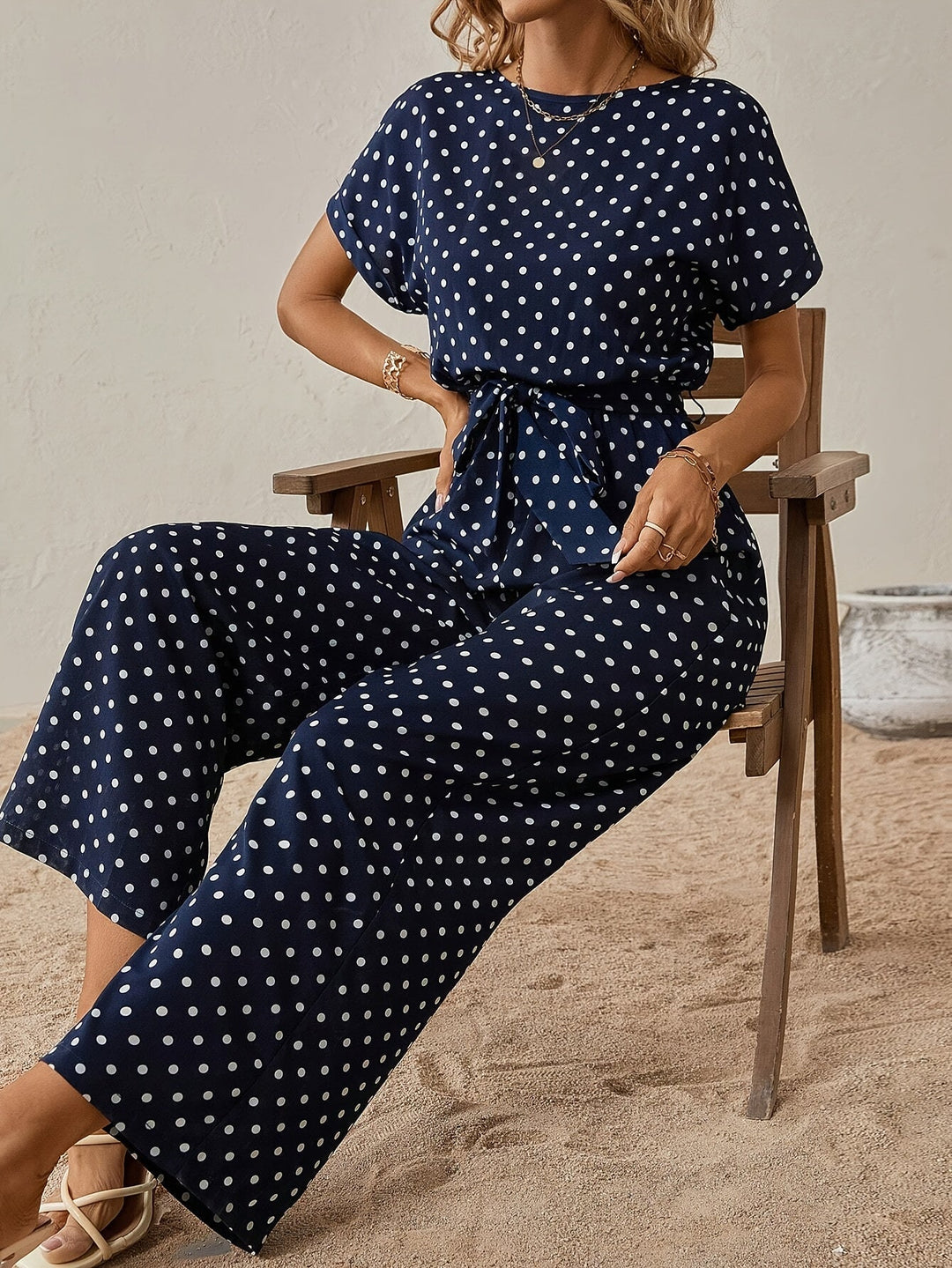 Stylowy kombinezon damski w kropki, z paskiem w talii, do eleganckich i casualowych letnich outfitów.